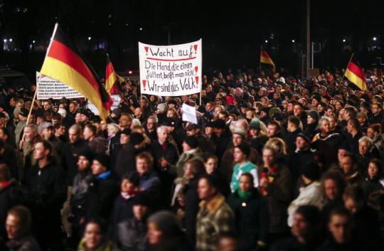 Participants hold German national flags and a banner during a demonstration called by anti-immigration group PEGIDA in Dresden